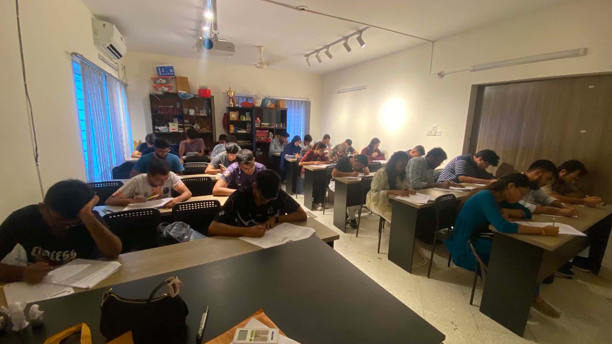 Students seated across a bright classroom taking an offline mock test