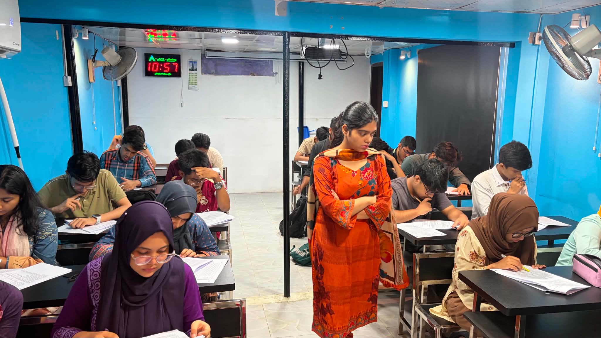 Students taking an offline mock test while an invigilator walks through the room